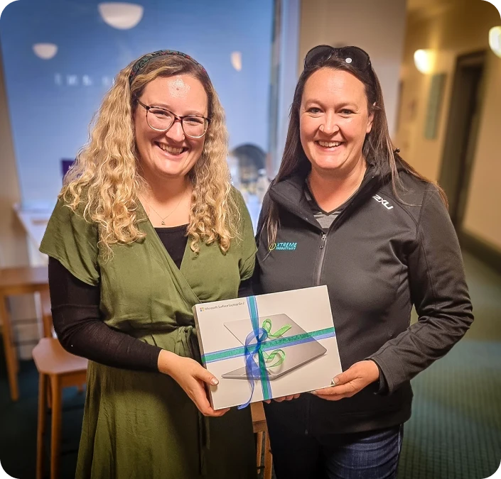 Xp staff and APO staff together, holding the laptop XP donated