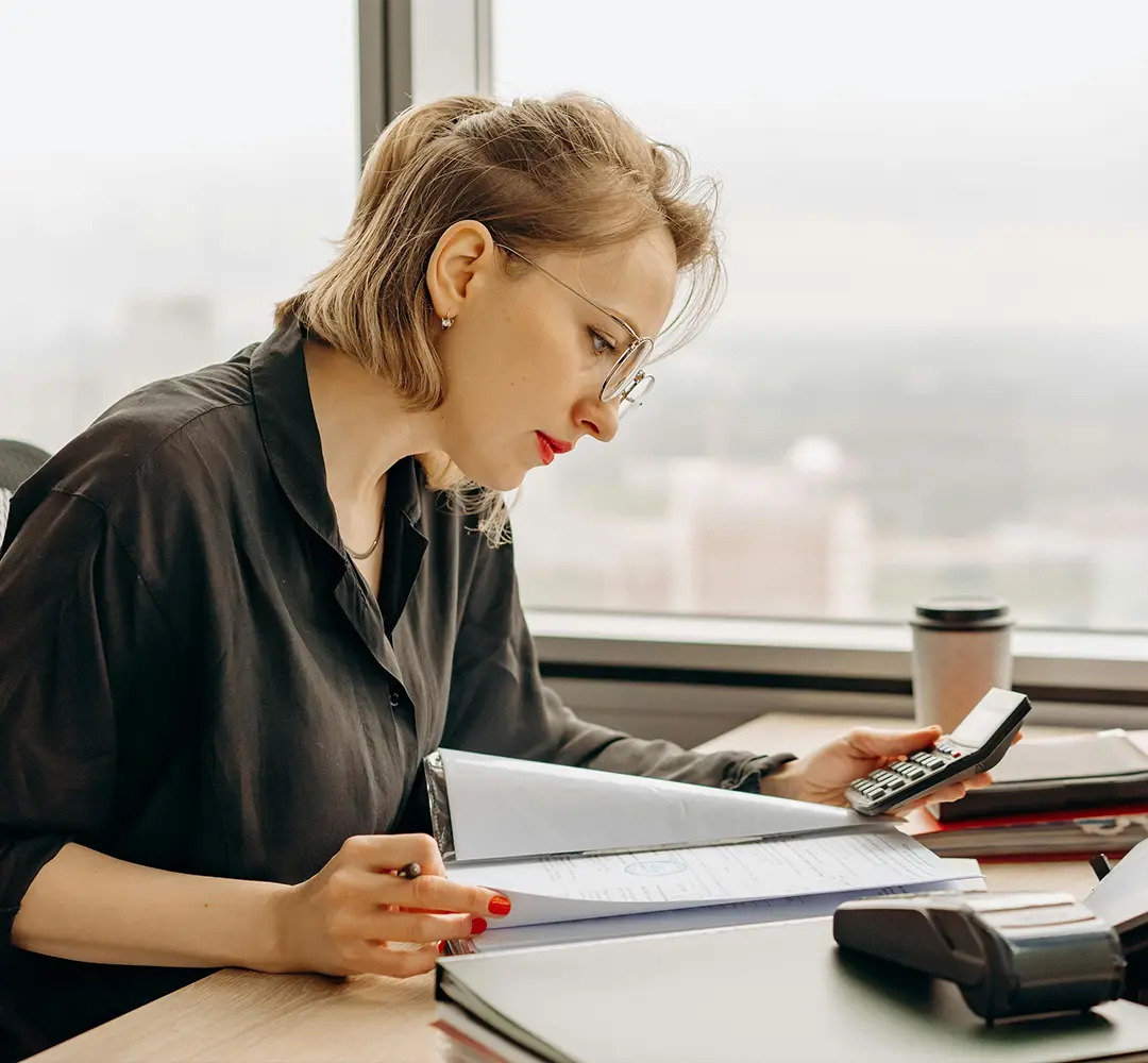 Woman sitting at desk with calculator and account records