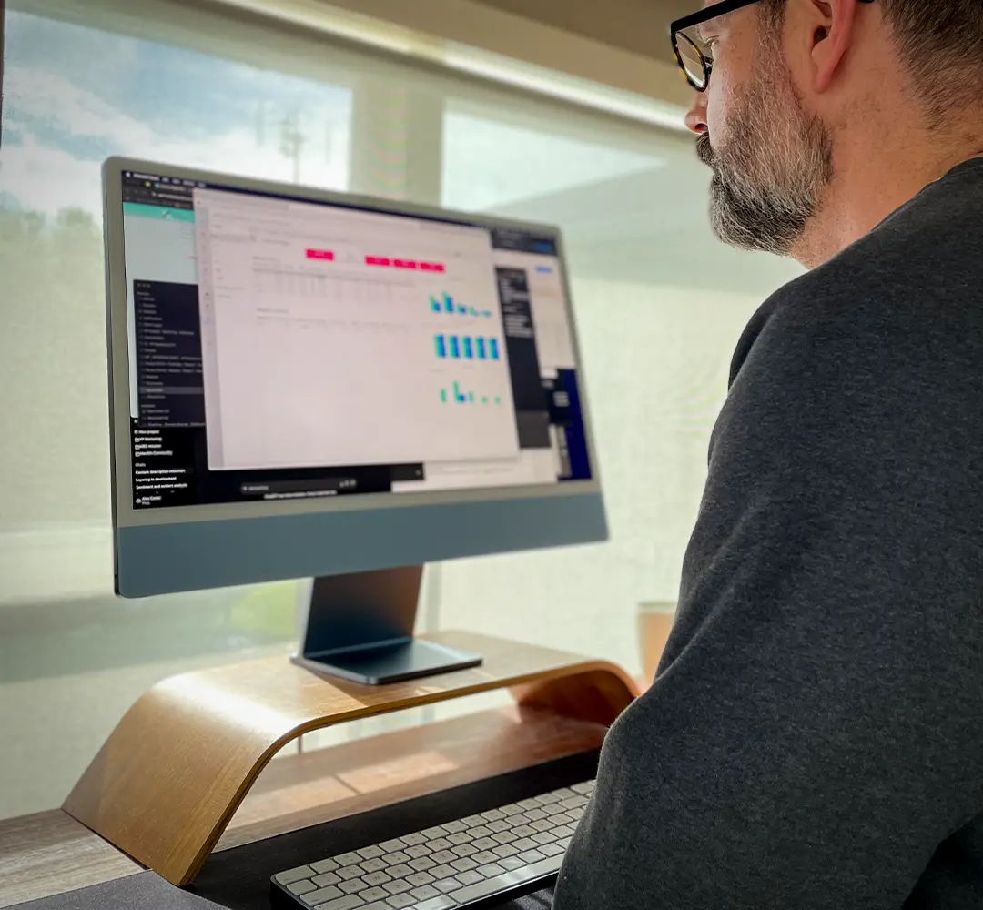 Man looking at a Power BI Dashboard in Microsoft Teams. He's at a standing desk in front of a window and the sun is streaming in.