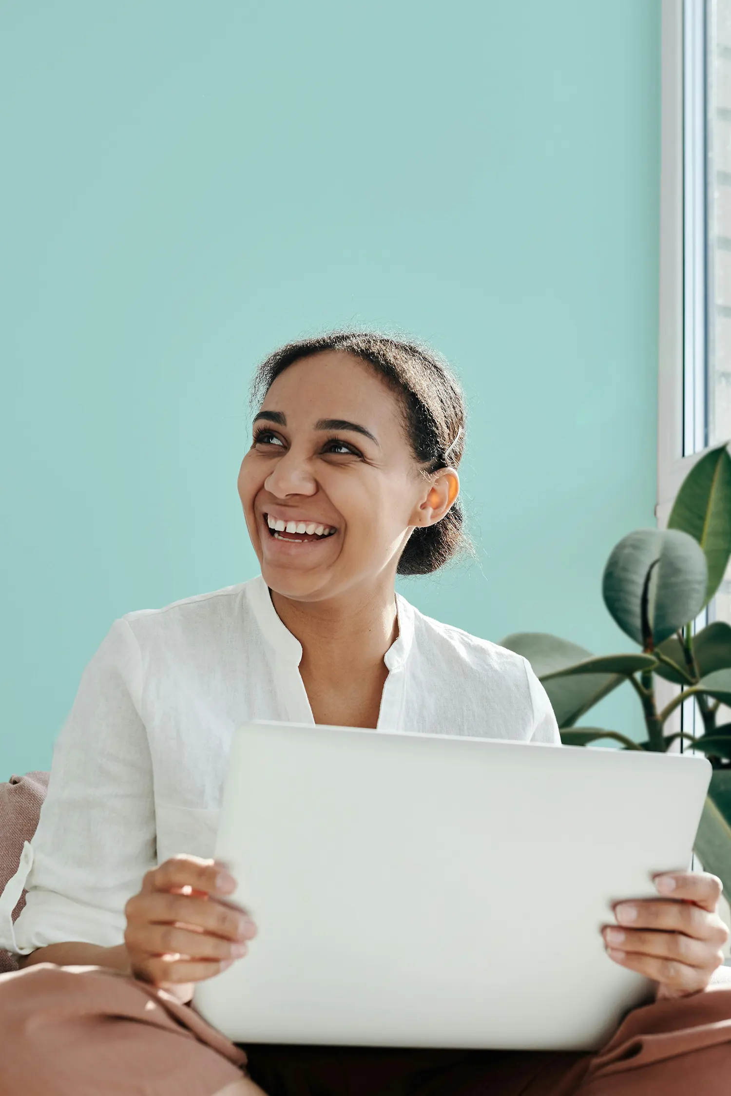 A woman sitting by a window with a laptop