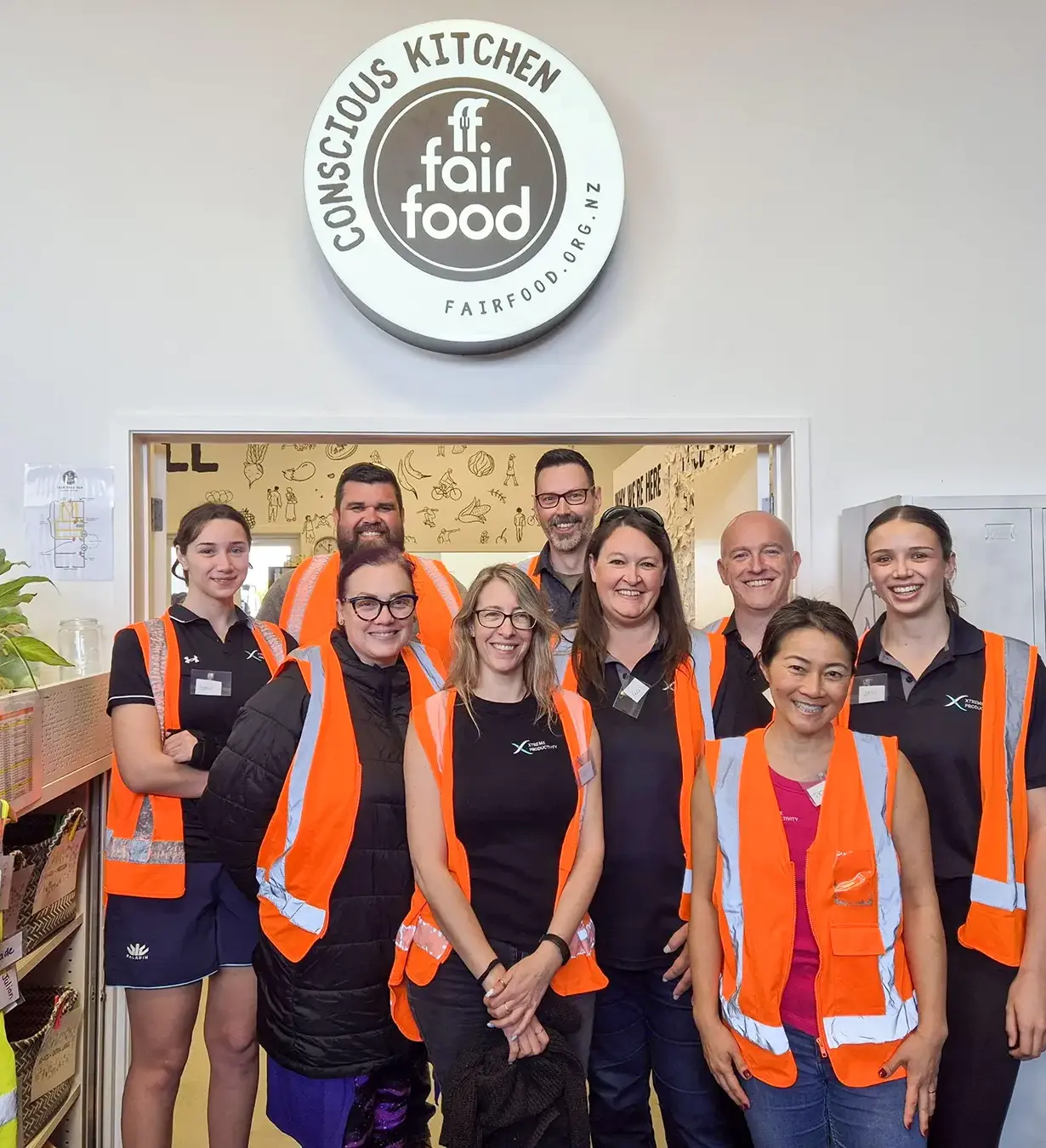 A group of men and women wearing orange vests in front of double doors with the 