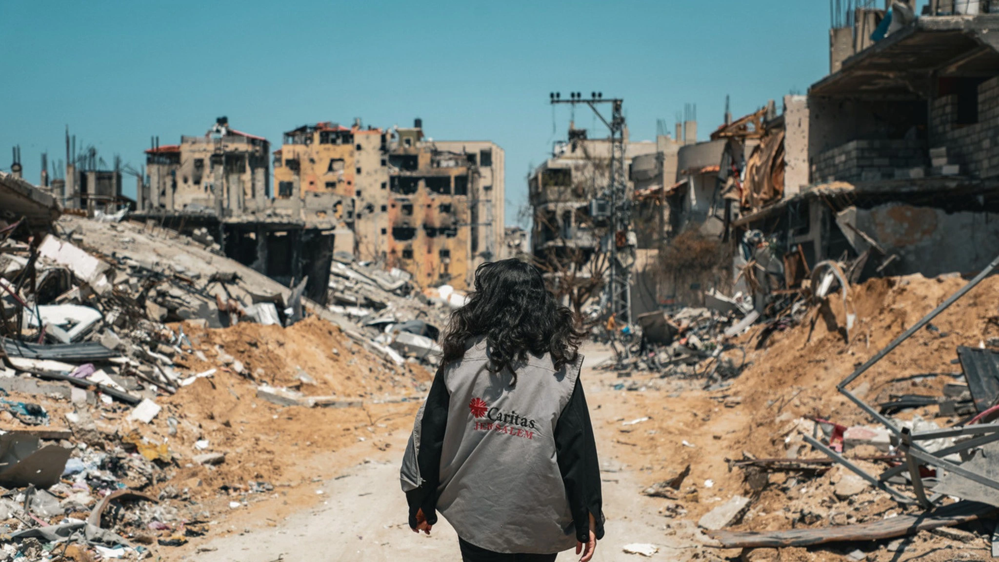 Volunteer walking through the middle of a city that has been destroyed, collapsed buildings, and rubbish on the streets