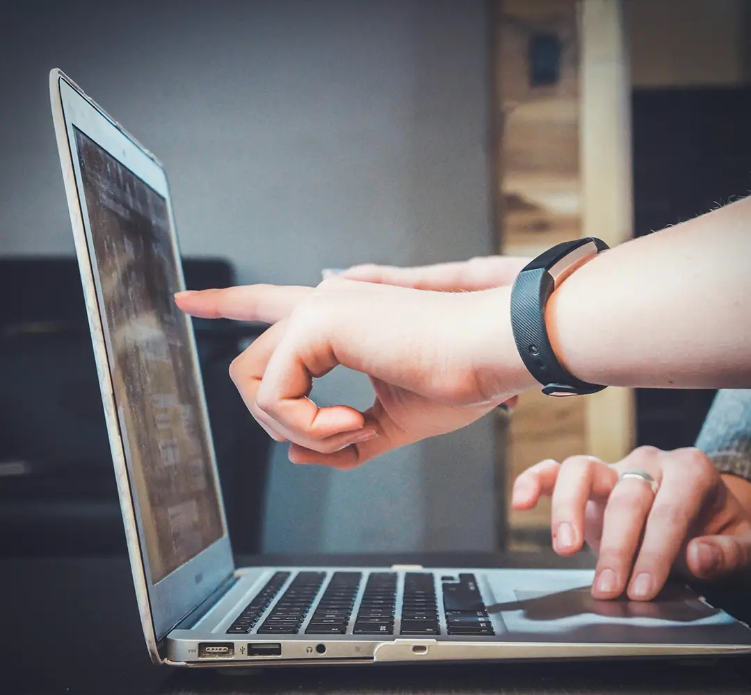 two hands pointing at a laptop screen