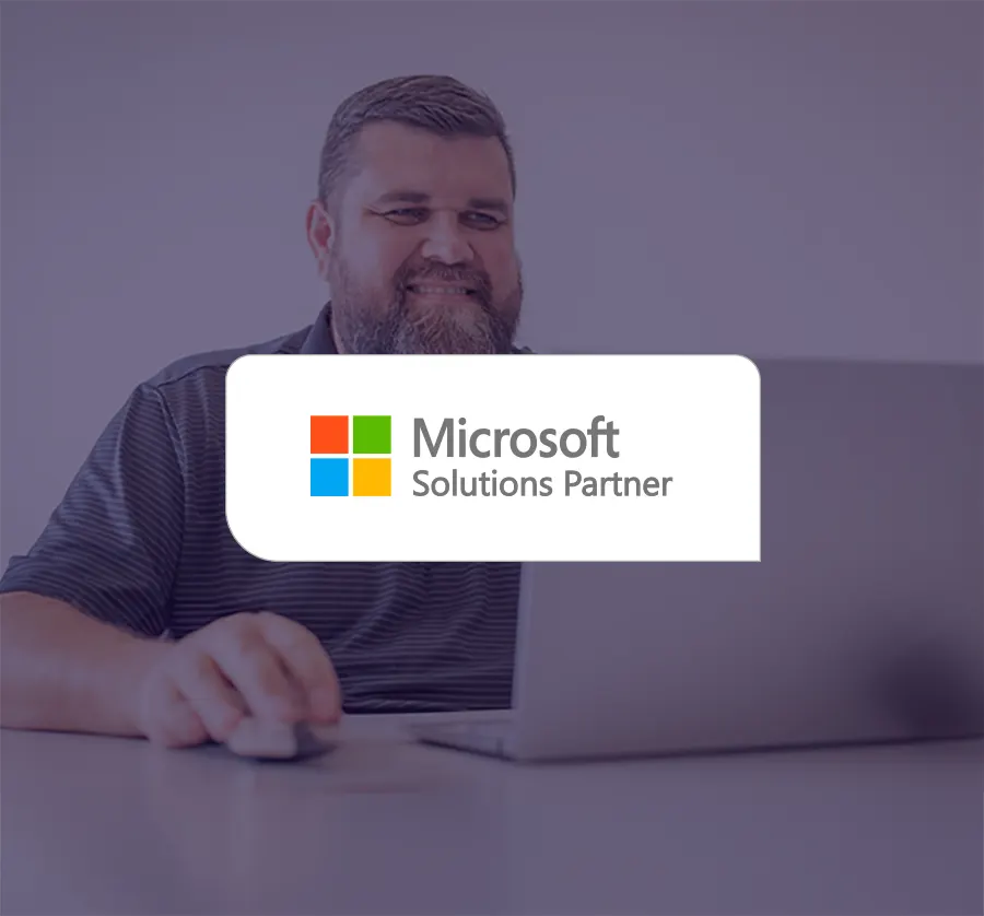 Man sitting at laptop, with Microsoft Solutions Partner badge