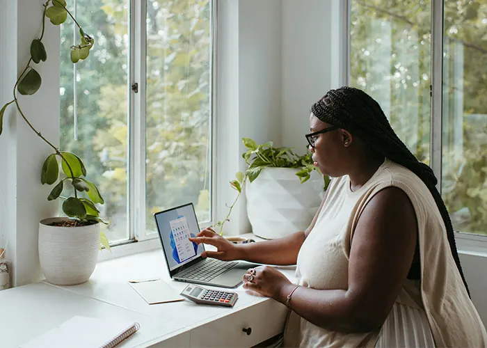 Woman sitting at a desk by a window using a laptop