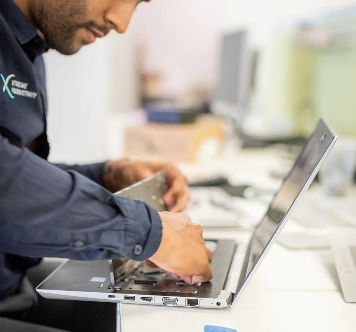 IT support worker from Xtreme Productivity working on fixing a laptop