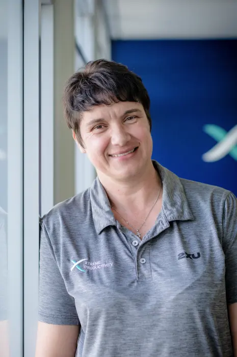 Sonja Binks leaning against a window in the office and smiling