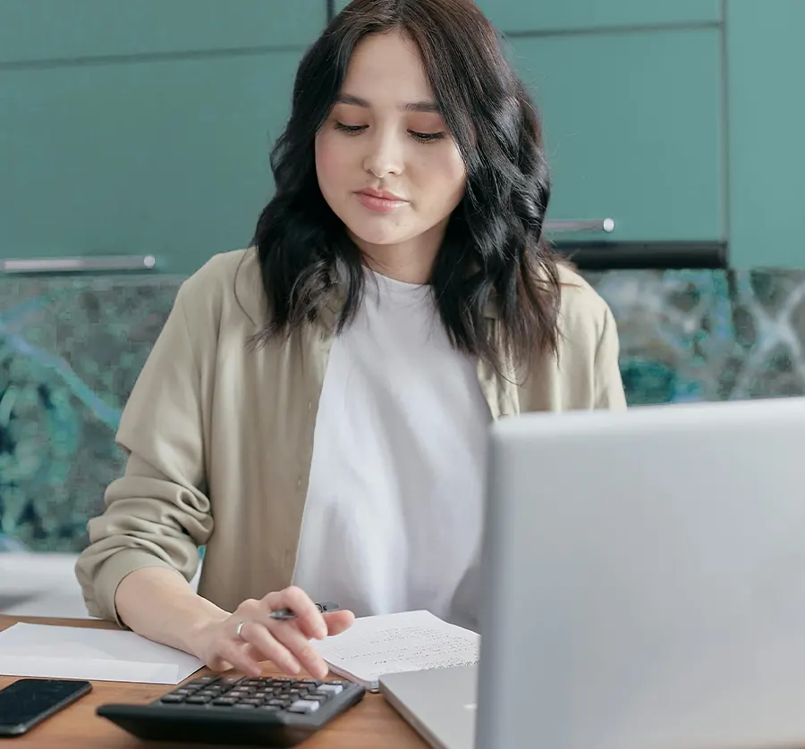 Woman checking xero nonprofit discount invoice with calculator and laptop 