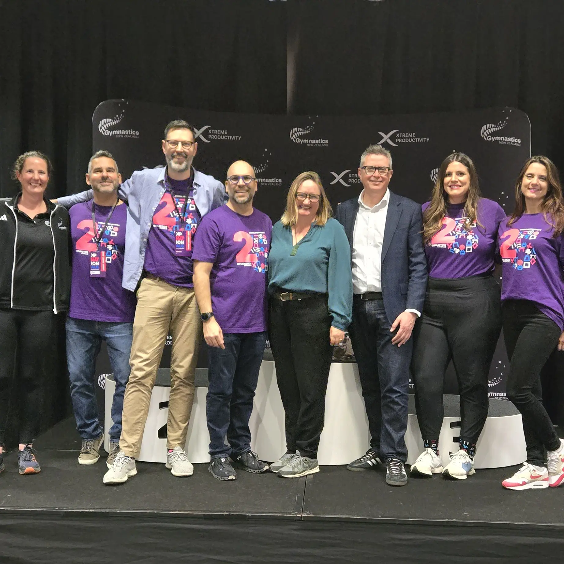 the xtreme productivity representatives and gymnastics new zealand team standing together in fron of a xp branded banner