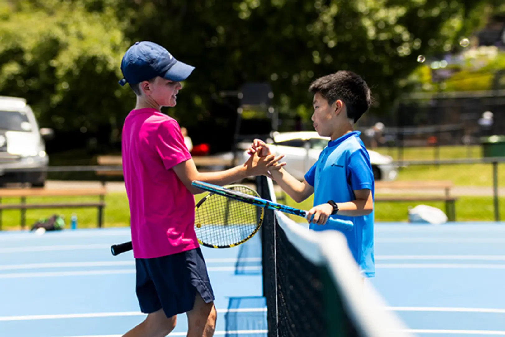 two kids shaking hands over the tennis court net